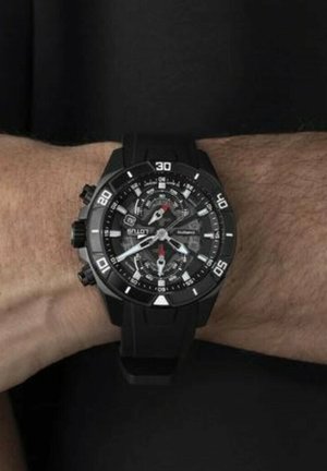 Montre en quartz noire avec un boîtier rond, un bracelet en caoutchouc et des marquages blancs ; elle présente des touches rouges et plusieurs cadrans pour la mesure du temps.