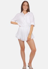 Chemise blanche à manches courtes texturée et shorts froncés assortis, fabriqués en tissu léger, avec un devant à boutons et un détail de poche.