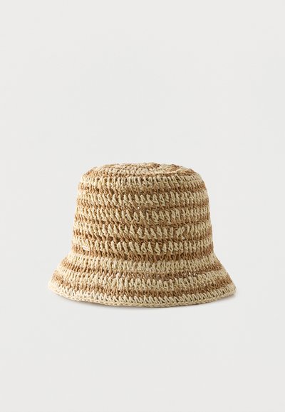 Πλεκτό καπέλο τύπου κάδος σε φυσικό μπεζ με καφέ ρίγες και με ελαφρώς φαρδύτερο γείσο, απεικονίζεται σε απλό ανοιχτό φόντο.
