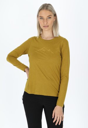 Mustard long-sleeve top with a rounded neckline and mountain graphic. Lightweight, soft texture paired with black pants, featuring side pockets.