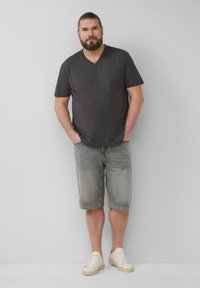Grijze v-hals t-shirt, lichtgrijze denimshorts en witte sneakers. De outfit is casual en heeft een ontspannen pasvorm met korte mouwen.