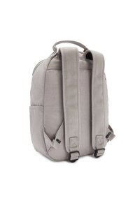 Mochila gris con correas de hombro acolchadas y un asa en la parte superior. Presenta una textura de tela suave y un bolsillo lateral. Diseño redondeado.