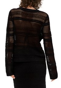 Czarny sweter dzianinowy z otwartym wzorem siatkowym, długimi rękawami i prążkowanymi mankietami. Wzór naprzemiennie przeplata się z jednolitymi sekcjami.