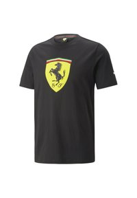 Camiseta de algodón negra con cuello redondo, que presenta un gran escudo del logo de Ferrari en amarillo en la parte frontal, y acentos en verde y rojo.
