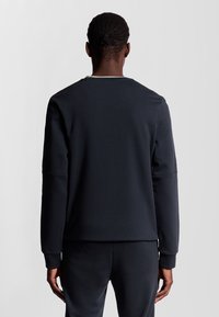 Felpa nera realizzata in materiale morbido, con colletto a girocollo e maniche lunghe. Texture liscia con cuciture minime.