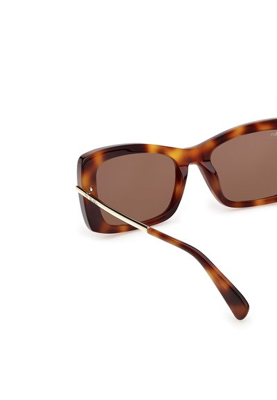 Lunettes de soleil écaille avec des verres carrés marron et des branches fines en métal de couleur dorée, présentées en angle sur un fond blanc.