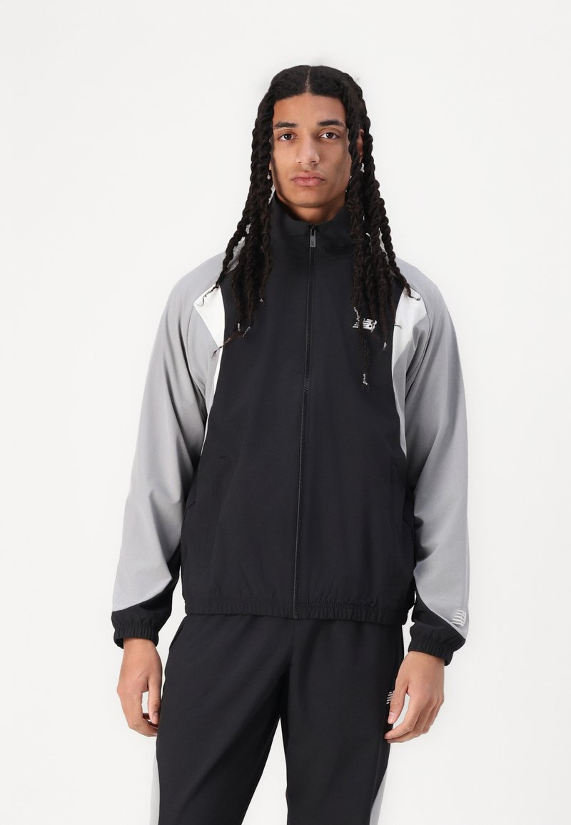 Black and gray windbreaker with a high collar, zip closure, elastic cuffs, and side pockets. Features a logo on the chest and shoulder.