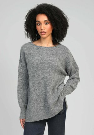 Pull gris ample avec un col rond et des manches longues. Il présente une texture douce et des fentes latérales à l'ourlet.