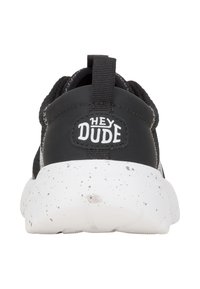 Schwarze Sneaker mit einer Gummisohle, die weiße Sprenkel aufweist, einem strukturierten schwarzen Obermaterial und einem auffälligen "HEY DUDE"-Logo an der Ferse.