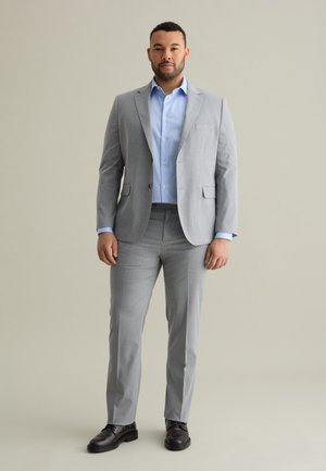 Light gray pinstriped suit with a single-breasted jacket, matching trousers, and a light blue shirt. Black shoes complete the look.