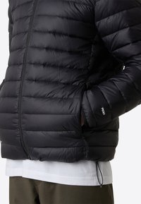 Giubbotto imbottito nero con design trapuntato, dotato di zip frontale, tasche laterali e orlo con cordino. Materiale morbido e leggero.