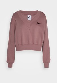 Beskuret, djup V-ringad sweatshirt i mauve, tillverkad av mjukt tyg. Långa ärmar med ribbade manschetter. Har en svart Nike-logotyp på bröstet.