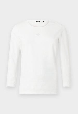 Hosszú ujjú fehér felső puha anyagból, kerek nyakkivágással és egy kis díszítéssel a mell résznél, finom csillogással.