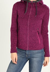 Fleece-huppari harmahtavassa magentassa värissä, jossa on huppu. Varustettu mustilla kiristysnaruilla, vetoketjullisilla taskuilla ja sileällä pinnalla.