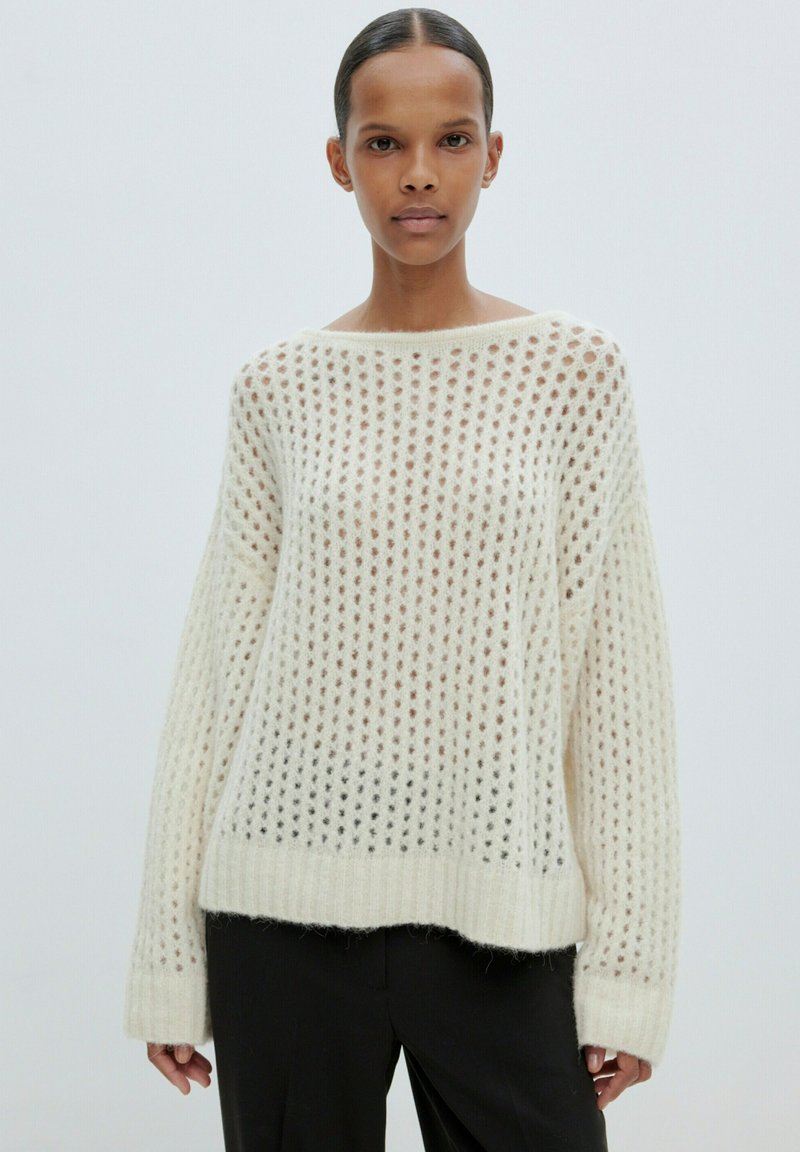 Cremefarbener, locker gestrickter Pullover mit weitem Halsausschnitt und langen Ärmeln, ausgestattet mit einem Wabenmuster und gerippten Bündchen und Saum.