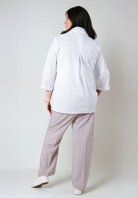 Witte blouse met een rugplooi, driekwartmouwen en lichtgrijze broek. De outfit heeft een losse pasvorm en een gladde stoftextuur.