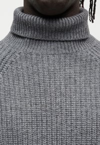 Γκρι πλεκτό πουλόβερ με υψηλό ζιβάγκο, διαθέτει ριμπ ύφανση και διακοσμητικά σχέδια. Μαλακό, ζεστό υλικό με εφαρμοστή σχεδίαση.