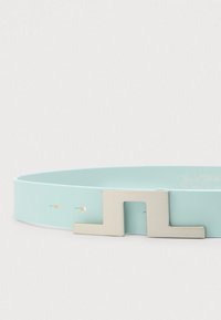 Φωτεινή γαλάζια συνθετική ζώνη με λεία υφή και ορθογώνιο ασημένιο μεταλλικό αγκράφα με σχέδιο κοπής. Πέντε ορατές τρύπες ρύθμισης.