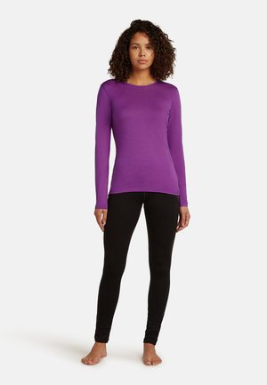 Paarse lange mouw top met een ronde hals, gecombineerd met zwarte leggings. De stof lijkt soepel en aansluitend, ontworpen voor comfort.