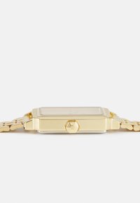 Montre rectangulaire en or avec un bracelet en maillons métalliques, affichant un cadran clair, un cadran simple et une couronne hexagonale sur le côté.
