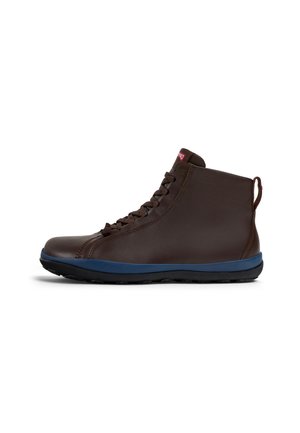 Botas de cuero marrón hasta el tobillo con suela de goma azul, punta redonda y diseño de cordones. Incluyen una lengüeta en la parte trasera para facilitar el calzado.