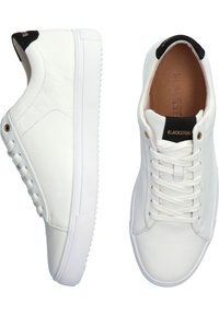 Sneaker bianco in pelle con texture liscia, dotato di un accento nera sul tallone, lacci piatti e suola in gomma spessa.