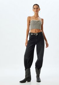 Sorte high-waisted jeans med en afslappet pasform, parret med en tætsiddende ternet cropped top og sorte broderede cowboy-støvler.