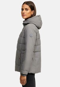 Grå puffjacka med huva, quiltat mönster, sidofickor och en logotyp på ärmen. Slätt och lätt material.