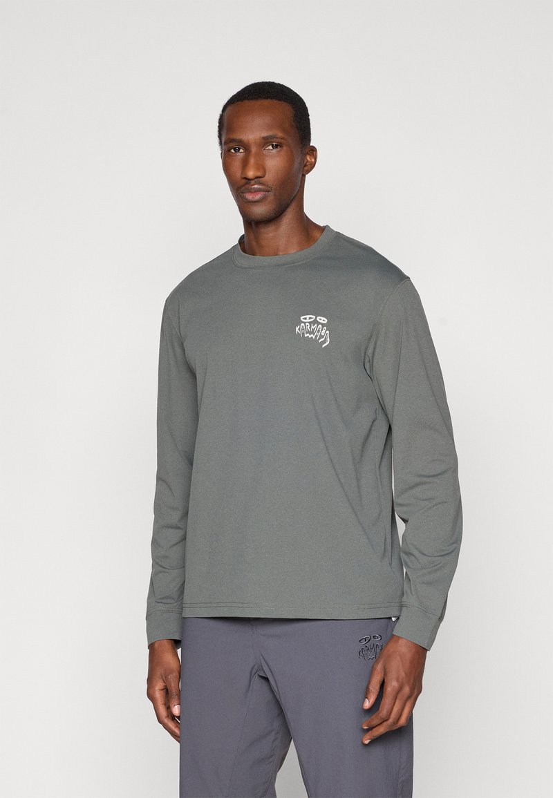 Camisa de manga longa em tecido cinza escuro com um logótipo gráfico branco no lado esquerdo do peito e um corte descontraído. Textura suave e design simples.