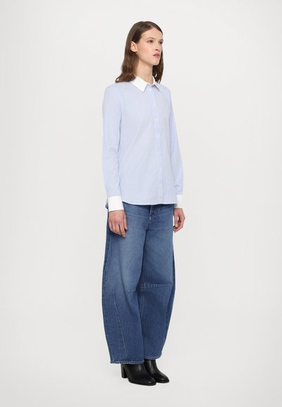 Light blue striped button-up shirt with a white collar, paired with loose blue denim jeans and black heeled ankle boots.