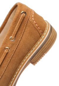 Suede shoes in light brown with stitching accents, round toe, and a rubber sole featuring a textured tread pattern and white trim.