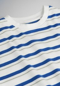 T-shirt blanc à col rond avec des rayures horizontales bleues et gris clair, présenté à plat sur un fond neutre.