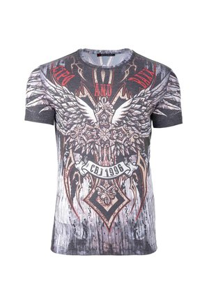 T-shirt graphique avec une base grise et un design audacieux, comprenant des ailes et des éléments ornementaux en rouge et noir, avec une apparence texturée.