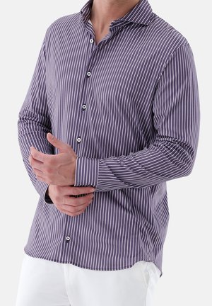 Man draagt een paarse overhemd met witte verticale strepen en knopen, past de manchetten aan, gecombineerd met witte broek.