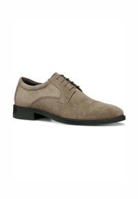 Zapato de vestir de ante marrón con una textura suave, puntera redondeada y suela de goma negra. Presenta cordones, costuras y un diseño de perfil bajo.
