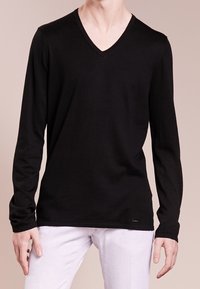 Maglietta nera a maniche lunghe con scollo a V realizzata in tessuto morbido, con un design aderente e un'etichetta logo discreta sul fondo.