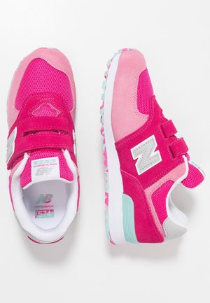 Pink- und fuchsienfarbene New Balance Kindersneaker mit Klettverschlüssen, weißen Mittelsolen und mehrfarbigen Gummiaußensohlen vor weißem Hintergrund.