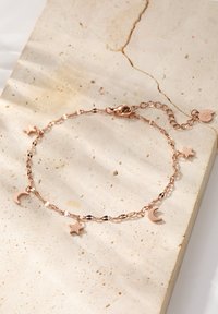 Brazalete de oro rosa con encantos alternos de estrella y luna creciente, con una cadena texturizada y un cierre de langosta seguro.