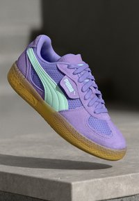 Sneakers Puma con una toma in suede viola e accenti menta, dettagli perforati e una suola in gomma naturale. Design classico con lacci.