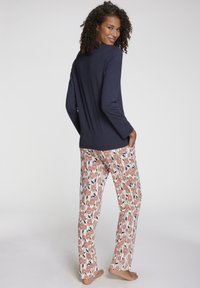 Navy long-sleeve top paired with white pants featuring a floral pattern in coral and navy. Soft fabric, relaxed fit, and side pockets.