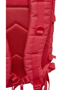 Punaisen repun yksityiskohta, jossa on teksturoitu verkkopaneeli, pehmustetut osat, säädettävät olkahihnat ja muoviset soljet turvalliseen kiinnitykseen.