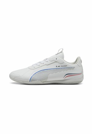 Sneaker sintetica bianca con pannello laterale perforato, dettagli blu e rossi, punta arrotondata, suola piatta e lacci. Presenta un'etichetta di tiraggio sul retro.