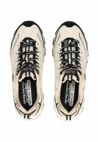 Beige Skechers sneakers met zwarte accenten, met geheugenschuim inlegzolen, gewatteerde tong en geventileerde mesh-secties, en een chunky zool.