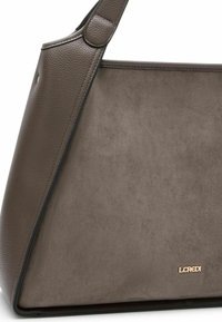 Borsa grigia in pelle testurizzata con finitura in camoscio liscia. Presenta una forma geometrica e un piccolo logo metallico sul davanti.