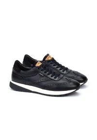 Zapatillas negras de cuero con detalles en ante, diseño con cordones, perforaciones y entresuela blanca. Presenta una etiqueta de marca en la lengüeta.