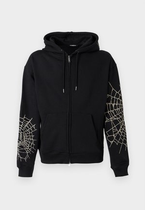 Fekete zipzáras kapucnis pulóver elülső zsebekkel és fehér pókhálós mintával mindkét ujján, húzózsinórral ellátott kapucnival.