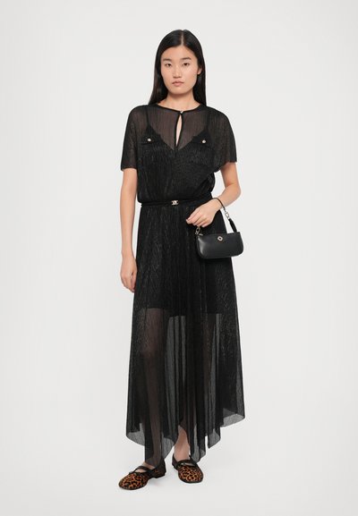 Zwarte doorzichtige maxi-jurk met korte mouwen, keyhole-halslijn en een ceintuur in de taille. Gecombineerd met slip-on schoenen met luipaardprint en een zwarte handtas.