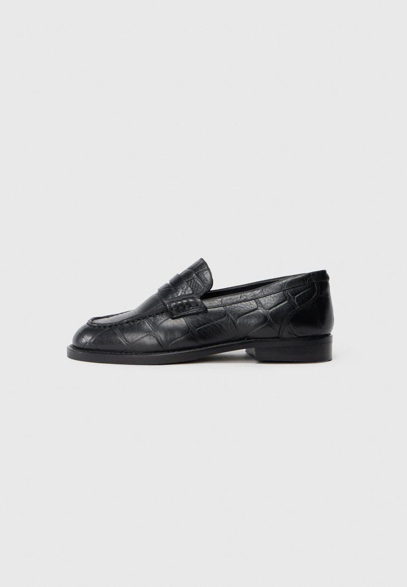 Schwarze Lederloafers mit einem strukturierten, krokodilähnlichen Muster, einem niedrigen Absatz und einer runden Zehe mit einem dekorativen Riemen.