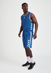 Niebieski sportowy top na ramiączkach i szorty z białymi paskami bocznymi oraz wzorami w chevron. Zawiera logo z przodu i charakteryzuje się dopasowanym krojem.