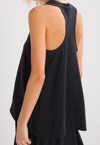 Tmavě šedý bezrukávový top s kulatým výstřihem a volně splývavým střihem. Měkká tkanina s hladkým povrchem a sníženými průramky.